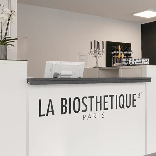 Empfangsbereich des Salons mit La Biosthétique Tresen und Orchidee